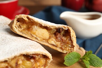 Delicious strudel with apples, nuts and raisins on wooden board, closeup