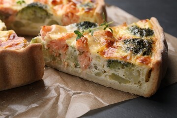 Delicious homemade quiche with salmon and broccoli on parchment paper, closeup