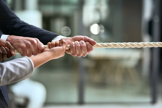 Hands, teamwork and rope with business people pulling during a game of tug of war in the office. Collaboration, help and strength with a team of employees or colleagues holding onto an opportunity