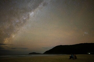 People sitting on the beach with a lantern under the stars, going star gazing, in Bondi, Sydney, Australia. On a family holiday trip down under