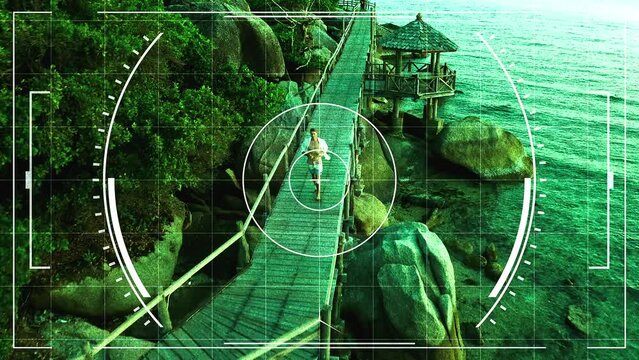Drone target screen tracking man running on boardwalk along sea cliffs.