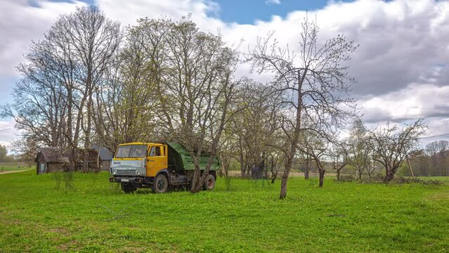 Gardening team pruning small garden and loading old Kamaz truck with branches