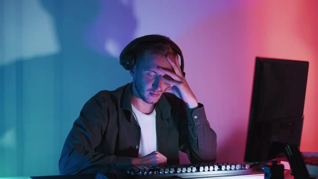 Upset gamer. Failure disappointment. Exhausted tired guy lost tournament on computer shaking head no seamless loop in dark neon light room.