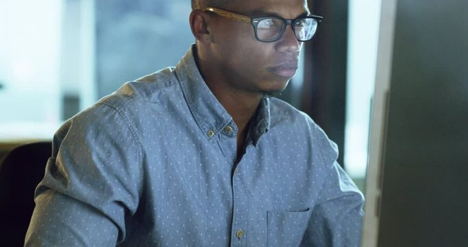 Computer, night and focus with a business man working late in his office on an overtime company project. Face, glasses and professional with a serious male employee sitting at his desk for work