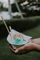 A serving of shave ice or snow cone with toppings and colorful s
