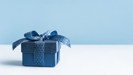 small Luxury gift box with a blue bow on light blue. Polka dot ribbon. Side view monochrome ....