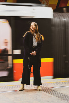 The white beautiful girl stands against the train in the metro