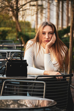Close up photo of beautiful girl sitting outside the caffe