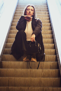 The white beautiful girl sitting on the escalator