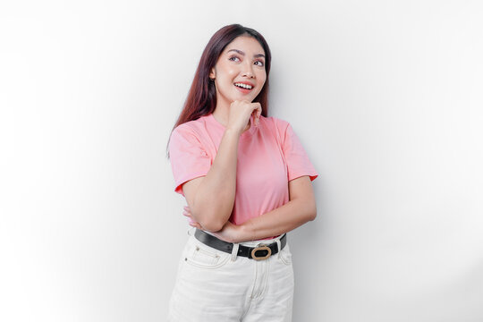 A thoughtful young woman is wearing pink t-shirt while looking aside, isolated by white background