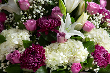 A view of a beautiful flower arrangement, featuring hydrangea, chrysanthemum, roses, lilies and baby's breath.