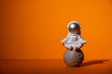 Plastic toy astronaut on colorful orange background Copy space. Concept of out of earth travel, private spaceman commercial flights. Space missions and Sustainability © anna.stasiia