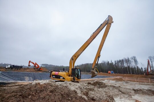 Ust-Luga, Leningrad oblast, Russia - November 16, 2021: Ground works and chemical waste ditch creation. Excavator Caterpillar with long boom