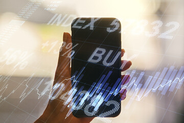 Multi exposure of abstract financial graph and hand with mobile phone on background, financial and trading concept