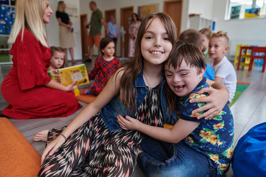 A girl and a boy with Down's syndrome in each other's arms spend time together in a preschool institution