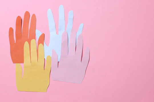 Multicolored paper hands on a pink background. The concept of Autism Day and Youth Solidarity Day.