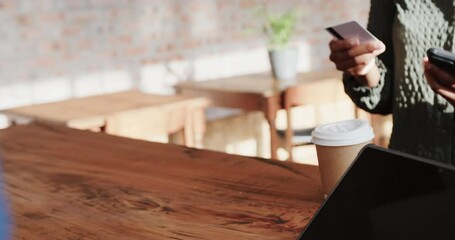 Midsection of african american woman paying with credit card at coffee shop, slow motion