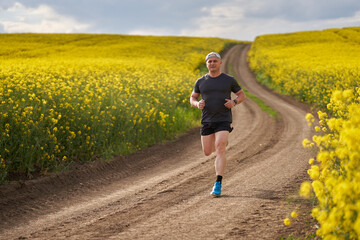 Distance runner running on a road through canola field