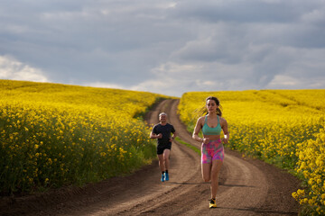Fototapeta premium Endurance runners on a dirt track in a canola field, training