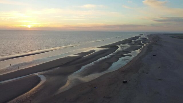 Water pools above low tide mark at ocean beach as sunsets peacefully in distance