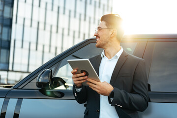 Young businessman using digital tablet while standing outdoors