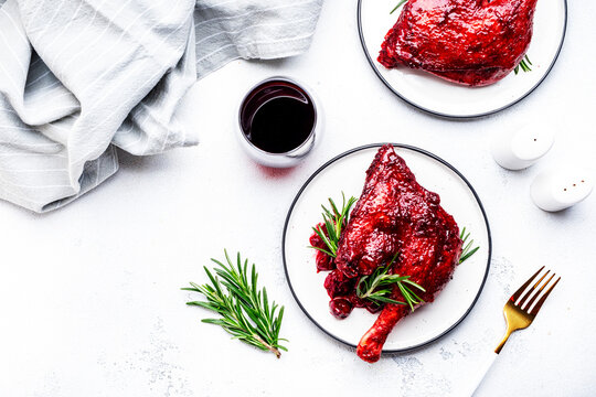 Baked duck legs in cherry and wine sauce with fresh rosemary. Gourmet dinner. White table background, top view