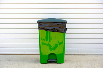 Green plastic garbage container standing in the street