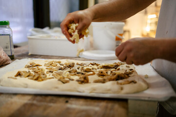 Hands adding ingredients to pizza