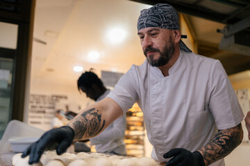 Baker placing balls of dough in a tray