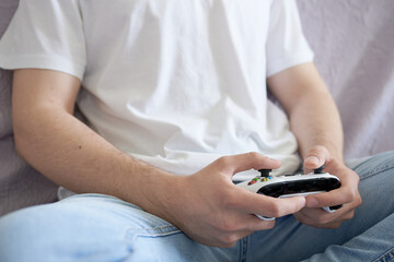 Young man playing video games with remote control on sofa at home.