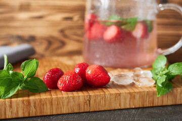 Strawberry drink with ice and mint on a wooden background.