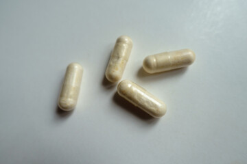 Macro of four light beige capsules of probiotic dietary supplement