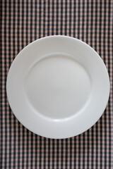 plain empty plate plain size on a traditional brown and black small checkered background, photography for menus and dinner posters.