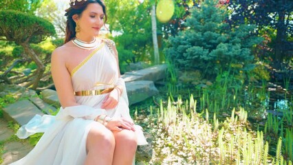 Portrait Fantasy happy woman greek goddess sits on river bank spring garden green tree nature sun light. Sexy girl queen antique style golden crown tiara diadem white silk long dress. red hair lady 4k - Powered by Adobe
