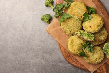 Delicious vegan cutlets with broccoli and parsley on light gray table, top view. Space for text