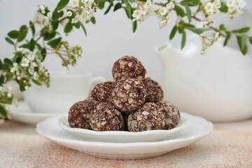 Delicious chocolate candies under blooming branch on beige table