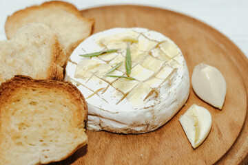 White baguette cut into pieces with olive oil and Camembert cheese on the table.