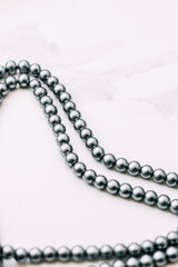 A necklace of gray beads on a white aesthetic background.