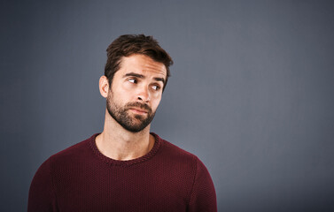 Doubt, thinking and face of unsure man in studio with worry, uncertain and thoughtful on gray background. Confused, mockup space and isolated male person skeptical for decision, choice and question