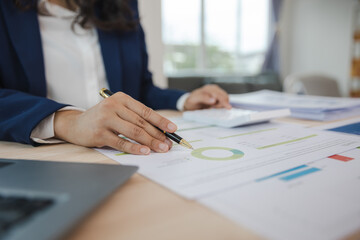 Close-up of asian businesswoman using calculator and laptop for mathematical finance on wooden table, tax, accounting, statistics and analytical research concept