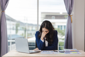 Asian woman stressed while working on laptop Tired Asian businesswoman having headache at office feeling sick at work