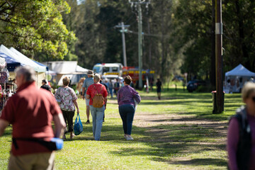 Weekend country market in a park in Australia. Family’s and people at a Farmers market selling...