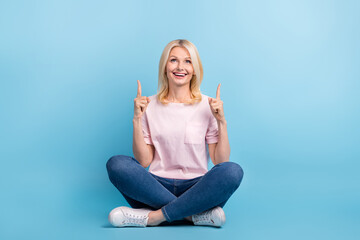 Full length photo of satisfied retired person t-shirt pants sitting directing look at sale empty space isolated on blue color background