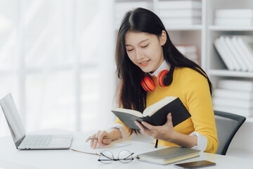 Happy young Asian woman working while reading book in the study room