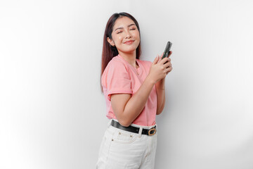 A portrait of a happy Asian woman is wearing pink t-shirt and holding her phone, isolated by white background