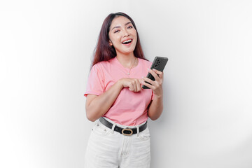 Fototapeta premium A portrait of a happy Asian woman is wearing pink t-shirt and holding her phone, isolated by white background