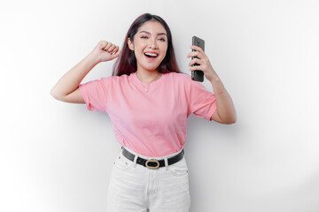 Fototapeta premium A young Asian woman with a happy successful expression wearing pink t-shirt and holding smartphone isolated by white background