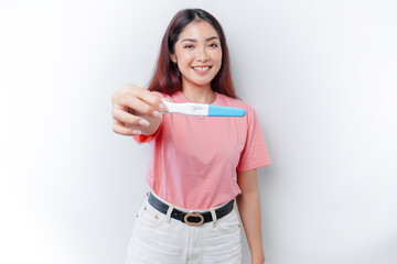 Happy young woman wearing pink t-shirt showing her pregnancy test and ultrasound picture, isolated on white background, pregnancy concept