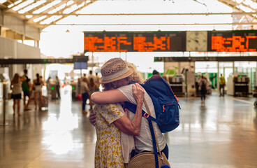 A couple of adult women embrace and say goodbye to each other at the train station.