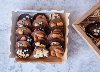 Round chocolate sweets with nuts (mediants) in a box. View from above. Light background.
